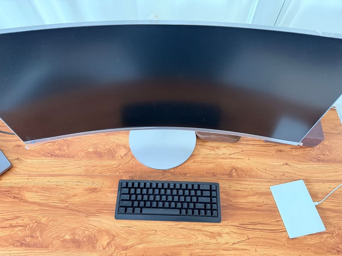 Top-down view of Epomaker HE68 Lite on a wooden desk next to a Magic Trackpad and curved monitor