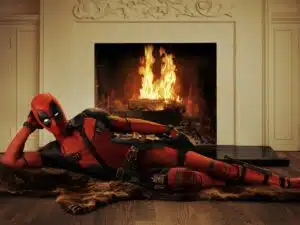 Deadpool lounging seductively by a fire.
